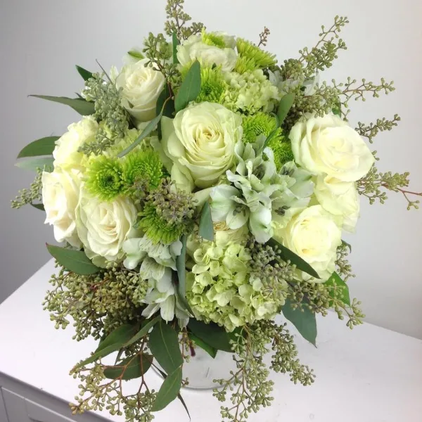 A lush floral arrangement with white roses, green chrysanthemums, and hydrangeas.