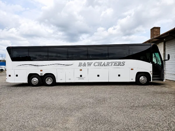 A white B&W Charters motorcoach bus parked on a gravel lot.