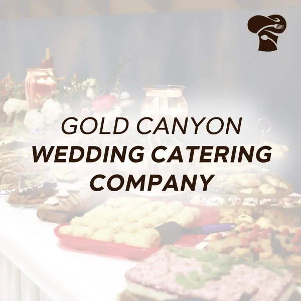 A catering buffet table with various food dishes and a floral arrangement.
