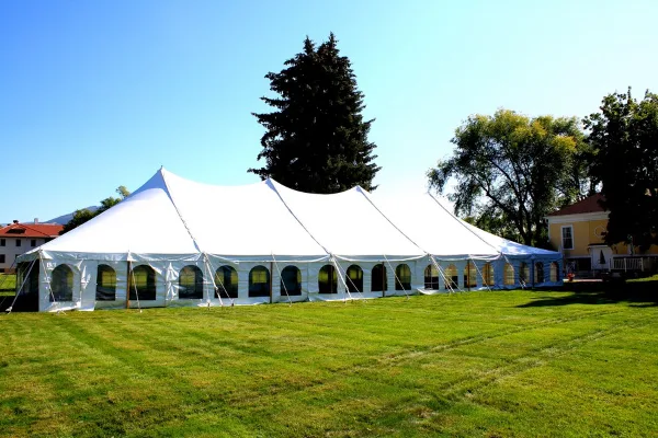 A large white event tent set up on a green lawn under a clear blue sky.