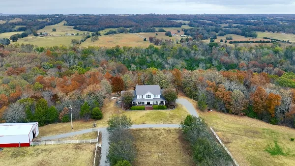 Aerial view of Garland Springs Manor showing the white manor house and red barn on a wooded property with valley views.