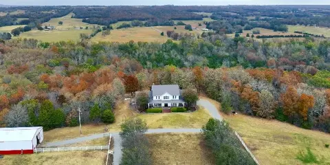 Aerial view of Garland Springs Manor showing the white manor house and red barn on a wooded property with valley views.