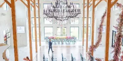 Interior view of a wedding venue with high wooden beams, a large chandelier, and floral arrangements.