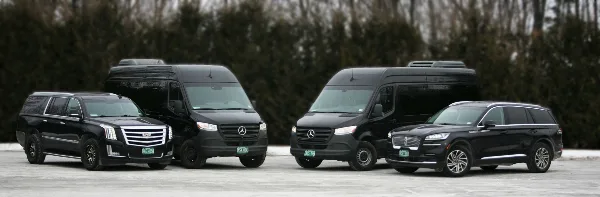 A lineup of four black luxury vehicles, including SUVs and limousines, parked on a paved surface.