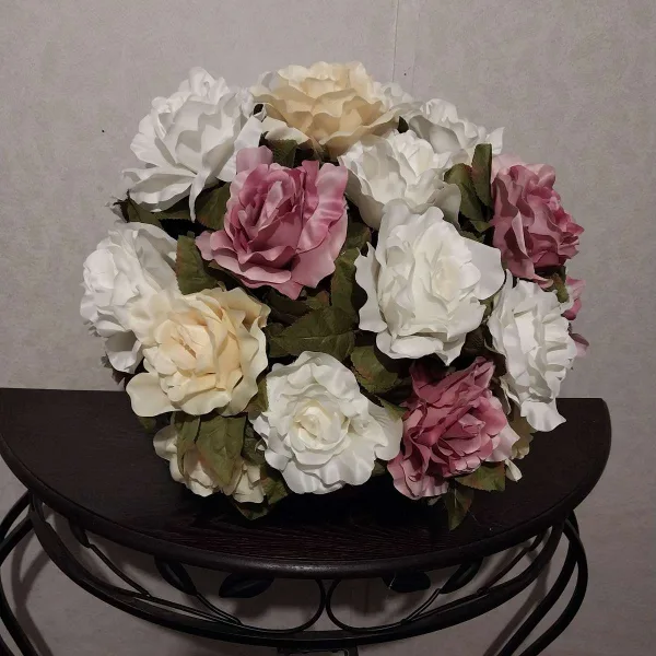 A floral arrangement of white and pink roses sitting on a dark wooden table.