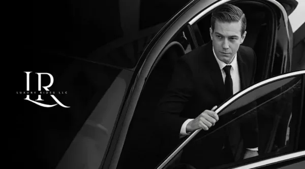 A professional chauffeur in a suit opening the door of a black luxury car.