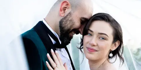 A bride and groom sharing an intimate moment, with the groom kissing the bride's forehead.