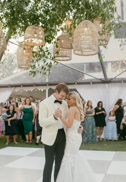 A bride and groom dancing at a wedding reception under hanging wicker lanterns.