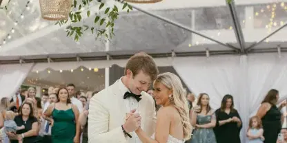 A bride and groom dancing at a wedding reception under hanging wicker lanterns.