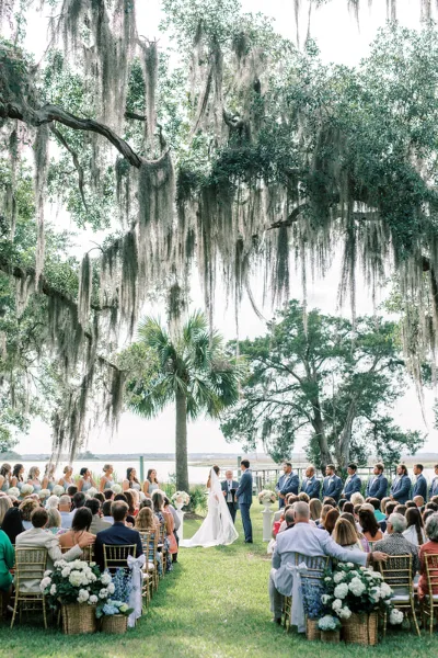 Outdoor wedding ceremony under live oaks with Spanish moss and river view