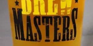 A pint glass of golden beer with the Brewmasters logo printed on the side.