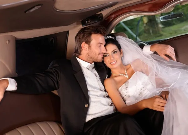 A bride and groom sitting together inside a luxury limousine.