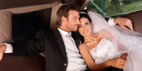 A bride and groom sitting together inside a luxury limousine.
