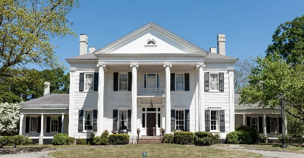 Exterior view of the white Bailey-Tebault House with columns and black shutters.