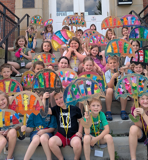 Children holding colorful fan-shaped art projects on the steps outside the Rowan County Arts Center