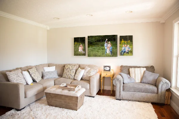 A living room with a sectional sofa and a three-panel family portrait gallery wall above it.