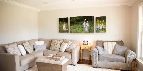 A living room with a sectional sofa and a three-panel family portrait gallery wall above it.