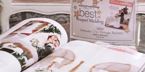 A 'Best of Newport Wedding 2020' award plaque for Uniquely Chic Vintage Rentals displayed next to an open magazine.