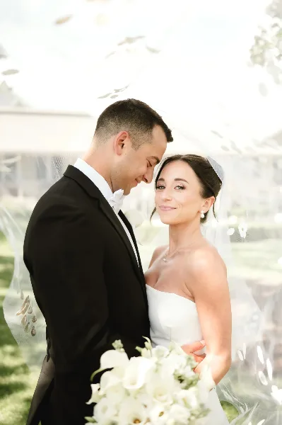 A bride with styled hair and makeup posing with her groom in a wedding portrait.