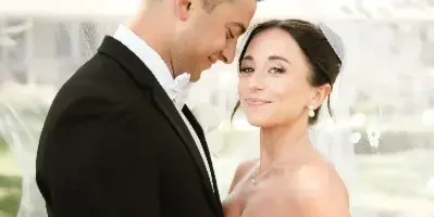 A bride with styled hair and makeup posing with her groom in a wedding portrait.