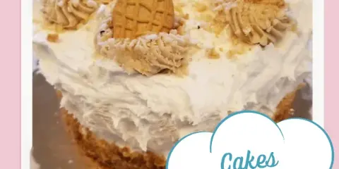 A close-up of a white frosted cake decorated with piped cream and whole cookies.