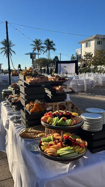 Outdoor catering display featuring a tiered grazing table with meats, cheeses, and fruit at a Southwest Florida event.