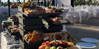 Outdoor catering display featuring a tiered grazing table with meats, cheeses, and fruit at a Southwest Florida event.