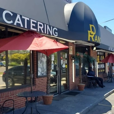 Exterior view of De Ranch Restaurant & Bar storefront with a 'CATERING' sign and outdoor seating.