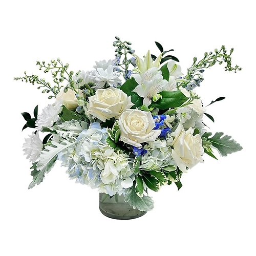 A white and blue floral arrangement featuring roses, hydrangeas, and lilies in a glass vase.