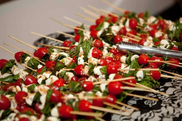 A large platter of caprese skewers with cherry tomatoes, mozzarella, and basil, ready for serving.