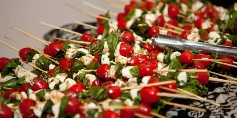 A large platter of caprese skewers with cherry tomatoes, mozzarella, and basil, ready for serving.