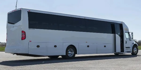 A white charter motor coach bus parked in a lot.