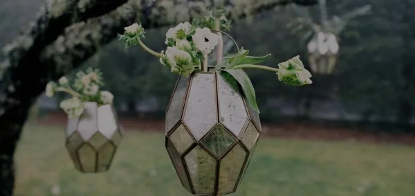 A floral arrangement with white flowers in a geometric glass vase.