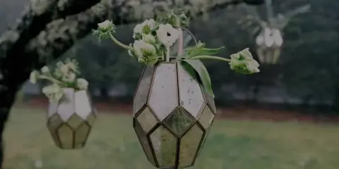A floral arrangement with white flowers in a geometric glass vase.