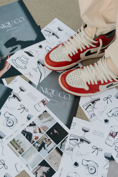 A close-up of Uniqu Co. Events branded stationery, a portfolio collage, and red and white sneakers.