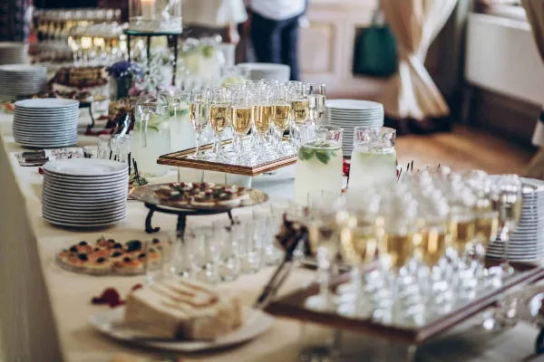 A catering table set with champagne flutes, hors d'oeuvres, and stacked plates.