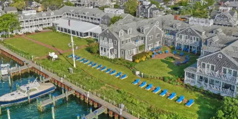Aerial view of the White Elephant Hotel resort on Nantucket, showing the main building, lawn with a white elephant statue, and a marina with boats.