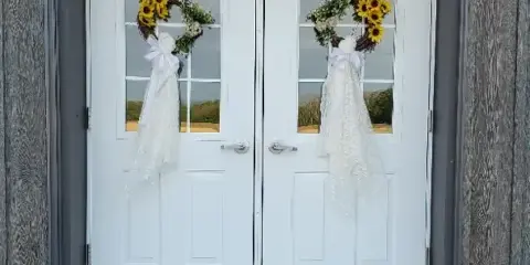 White double doors with sunflower wreaths on a rustic wooden building exterior
