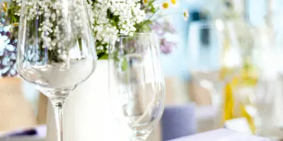 A floral centerpiece featuring white and purple flowers on a decorated event table with glassware.