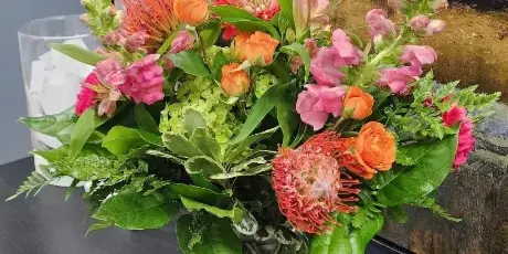 A colorful floral arrangement in a glass vase with a Flower Mill card inserted.