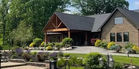 Exterior view of Stone Creek Lodge venue building with stone facade, wooden entry, landscaped gardens, and a small water feature in the foreground.