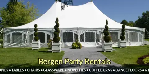 A large white event tent set up on a grassy lawn with tables and topiary decorations.