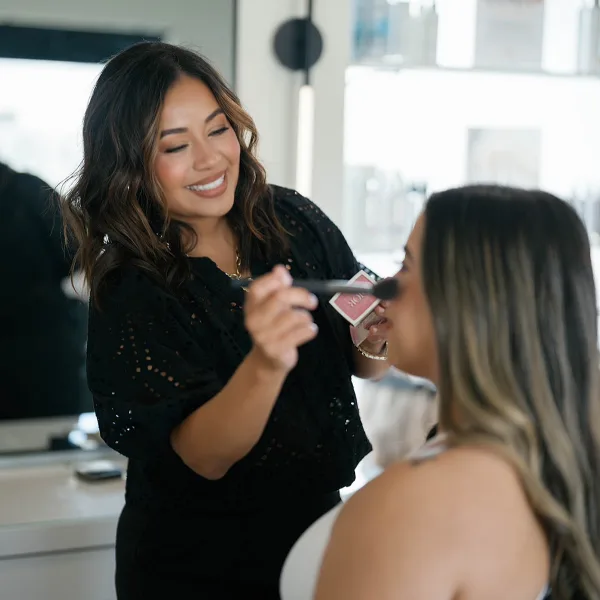 A makeup artist applying makeup to a client in a studio setting.