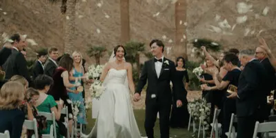 Bride and groom walking down the aisle at a wedding ceremony with guests seated on either side.