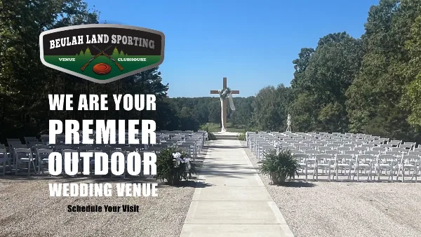 Outdoor wedding ceremony setup with rows of white chairs and a large cross in the background.