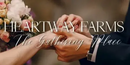 Close-up of a bride and groom clasping hands during a wedding ring exchange, with a floral bouquet visible.