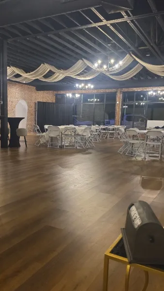Interior view of a wedding venue with exposed brick walls, wooden floors, and tables set for an event.