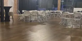 Interior view of a wedding venue with exposed brick walls, wooden floors, and tables set for an event.
