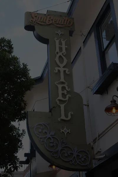 Exterior sign for the San Benito Hotel attached to a building facade.