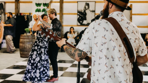 A couple dancing at a wedding reception while a musician plays guitar in the foreground.
